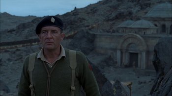 Movie still from “Dominion: Prequel to the Exorcist” (2005), directed by Paul Schrader – A man in a military uniform standing in front of a building; Medium shot, Low angle