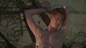 Movie still from “Dominion: Prequel to the Exorcist” (2005), directed by Paul Schrader – A man with a knife stuck to his chest; Medium shot, Low angle