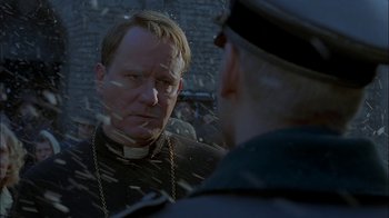 Movie still from “Dominion: Prequel to the Exorcist” (2005), directed by Paul Schrader – A man in a priest's outfit talking to another man in a uniform; Close Up shot, Over the shoulder angle