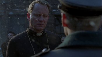 Movie still from “Dominion: Prequel to the Exorcist” (2005), directed by Paul Schrader – A man wearing a priest's collar and a chain around his neck; Close Up shot, Over the shoulder angle