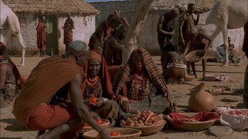 Movie still from “Dominion: Prequel to the Exorcist” (2005), directed by Paul Schrader – A group of people sitting on the ground with baskets of food; Medium shot, High angle
