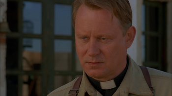 Movie still from “Dominion: Prequel to the Exorcist” (2005), directed by Paul Schrader – A man in a priest's outfit looking at the camera; Close Up shot, Low angle