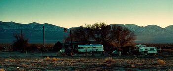 Movie still from “Domino” (2005), directed by Tony Scott – An rv parked in the middle of a field with mountains in the background; Extreme Wide shot, Low angle