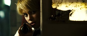 Movie still from “Domino” (2005), directed by Tony Scott – A young woman talking on a phone while standing in a room; Close Up shot, Over the shoulder angle