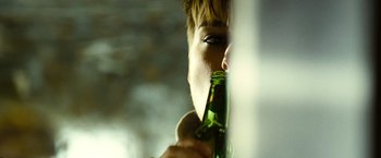 Movie still from “Domino” (2005), directed by Tony Scott – A man drinking a beer from a green bottle; Extreme Close Up shot, Over the shoulder angle