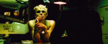 Movie still from “Domino” (2005), directed by Tony Scott – A woman sitting in front of a table with a cigarette in her mouth; Close Up shot, Low angle