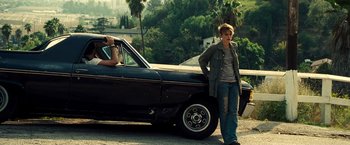Movie still from “Domino” (2005), directed by Tony Scott – A woman standing next to an old black car; Wide shot, Over the shoulder angle