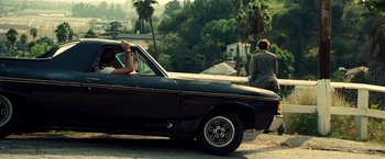Movie still from “Domino” (2005), directed by Tony Scott – A woman sitting in the driver's seat of an old car; Wide shot, Over the shoulder angle