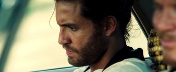 Movie still from “Domino” (2005), directed by Tony Scott – A person with a beard; Close Up shot, Over the shoulder angle