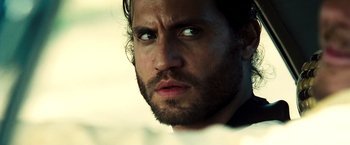 Movie still from “Domino” (2005), directed by Tony Scott – A person with a beard; Close Up shot, Over the shoulder angle