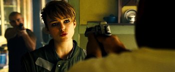 Movie still from “Domino” (2005), directed by Tony Scott – A person holding a gun in front of a mirror; Close Up shot, Over the shoulder angle
