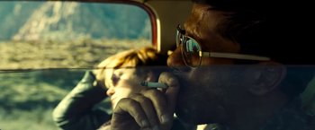 Movie still from “Domino” (2005), directed by Tony Scott – A man smoking a cigarette in a car with a woman sitting in the back seat; Extreme Close Up shot, Low angle