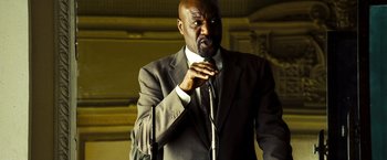 Movie still from “Domino” (2005), directed by Tony Scott – A man in a gray suit and a white tie; Medium shot, Low angle