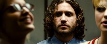 Movie still from “Domino” (2005), directed by Tony Scott – A person with long curly hair; Close Up shot, Over the shoulder angle