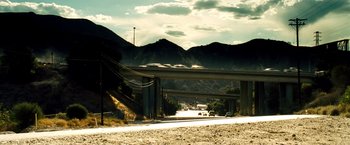 Movie still from “Domino” (2005), directed by Tony Scott – A highway with cars driving on it and a bridge in the background; Extreme Wide shot, Low angle