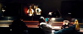 Movie still from “Domino” (2005), directed by Tony Scott – A man sitting in front of a sound board; Wide shot, Low angle