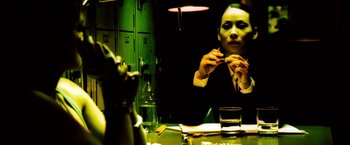 Movie still from “Domino” (2005), directed by Tony Scott – A woman sitting at a table with a glass of water; Close Up shot, Low angle