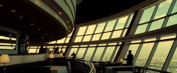 Movie still from “Domino” (2005), directed by Tony Scott – People are sitting in a restaurant with a view of the ocean; Extreme Wide shot, Low angle