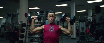 Movie still from “Don Jon” (2013), directed by Joseph Gordon-Levitt – A man is lifting two dumbbells in a gym; Medium shot, Low angle