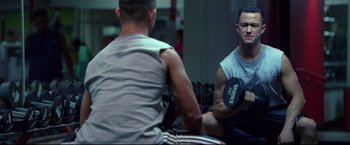 Movie still from “Don Jon” (2013), directed by Joseph Gordon-Levitt – A man holding a dumbbell while sitting next to another man in front of a mirror; Medium shot, Over the shoulder angle