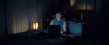 Movie still from “Don Jon” (2013), directed by Joseph Gordon-Levitt – A man sitting on a bed using a laptop computer; Medium shot, High angle
