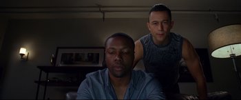 Movie still from “Don Jon” (2013), directed by Joseph Gordon-Levitt – Two men sitting in front of each other in a dark room; Medium shot, High angle