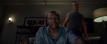 Movie still from “Don Jon” (2013), directed by Joseph Gordon-Levitt – A man sitting in front of another man in a living room; Medium shot, Low angle