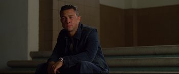 Movie still from “Don Jon” (2013), directed by Joseph Gordon-Levitt – A man sitting on some steps wearing a jean jacket; Medium shot, High angle