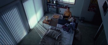 Movie still from “Don Jon” (2013), directed by Joseph Gordon-Levitt – A man sitting on top of a bed in a bedroom; Wide shot, High angle
