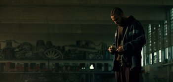 Movie still from “Don't Breathe” (2016), directed by Fede Alvarez – A man standing in the dark looking at his cell phone; Medium shot, Low angle