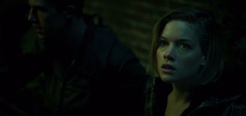 Movie still from “Don't Breathe” (2016), directed by Fede Alvarez – A woman is looking at the camera while a man is sitting behind her; Close Up shot, Over the shoulder angle