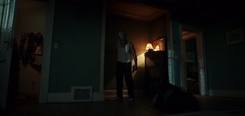 Movie still from “Don't Breathe” (2016), directed by Fede Alvarez – A man standing in a dark room holding a game controller; Wide shot, Low angle