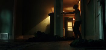 Movie still from “Don't Breathe” (2016), directed by Fede Alvarez – A man standing on the floor in front of a sleeping man; Wide shot, Low angle