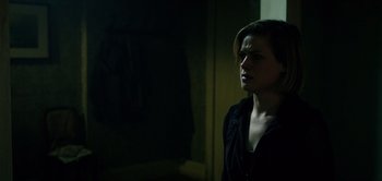 Movie still from “Don't Breathe” (2016), directed by Fede Alvarez – A woman standing in a dark room with her head turned to the side; Close Up shot, Over the shoulder angle