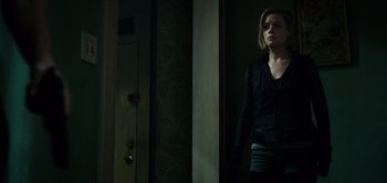 Movie still from “Don't Breathe” (2016), directed by Fede Alvarez – A woman standing next to a door in a dark room; Medium shot, Over the shoulder angle