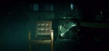 Movie still from “Don't Breathe” (2016), directed by Fede Alvarez – A chair and a fan in a dark room; Wide shot, High angle