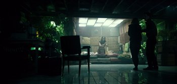 Movie still from “Don't Breathe” (2016), directed by Fede Alvarez – A woman sitting on a bed in a dark room; Wide shot, Low angle