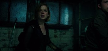Movie still from “Don't Breathe” (2016), directed by Fede Alvarez – A woman in a dark room looking at the camera; Medium shot, Low angle