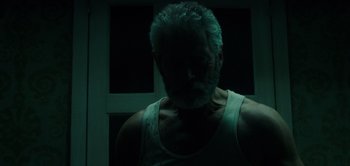 Movie still from “Don't Breathe” (2016), directed by Fede Alvarez – A man in a white tank top is in a dark room; Close Up shot, Low angle