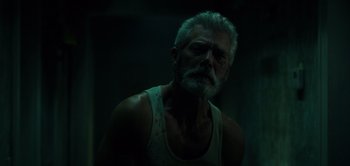 An old man with a beard and a white tank top