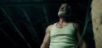 Movie still from “Don't Breathe” (2016), directed by Fede Alvarez – An old man with a beard and a white tank top; Medium shot, Low angle