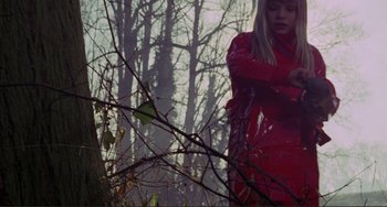 Movie still from “Don't Look Now” (1973), directed by Nicolas Roeg – A woman in a red coat standing in front of trees; Medium shot, Low angle