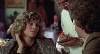Movie still from “Don't Look Now” (1973), directed by Nicolas Roeg – A woman sitting in front of two men writing on a piece of paper; Close Up shot, Over the shoulder angle