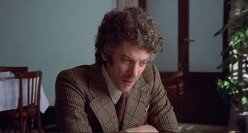 Movie still from “Don't Look Now” (1973), directed by Nicolas Roeg – A man in a suit and tie sitting at a table; Close Up shot, Over the shoulder angle