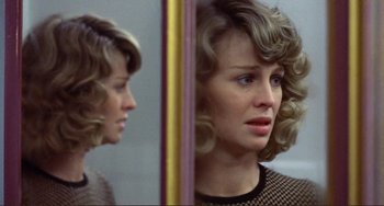 Movie still from “Don't Look Now” (1973), directed by Nicolas Roeg – A woman with blonde curly hair looking in the mirror; Close Up shot, Over the shoulder angle