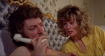 Movie still from “Don't Look Now” (1973), directed by Nicolas Roeg – A man and a woman sitting next to each other on a phone; Close Up shot, Over the shoulder angle