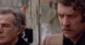 Movie still from “Don't Look Now” (1973), directed by Nicolas Roeg – A man with a beard and mustache is looking at another man with a beard and mustache; Close Up shot, Over the shoulder angle