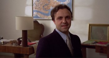 Movie still from “Don't Look Now” (1973), directed by Nicolas Roeg – A man in a suit and tie in front of a map; Close Up shot, Low angle