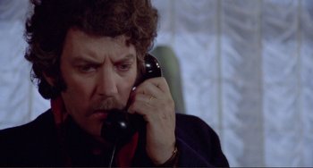 Movie still from “Don't Look Now” (1973), directed by Nicolas Roeg – A man talking on a phone while sitting down; Close Up shot, Low angle