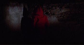 Movie still from “Don't Look Now” (1973), directed by Nicolas Roeg – A person wearing a red hooded sweatshirt in the dark; Medium shot, High angle
